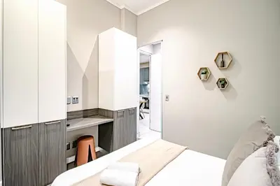 a small bedroom with a bed and a desk at Penthouse and Apartment at The Capital Triology Menlyn Maine in Pretoria