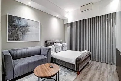 a living room with a couch and a bed and a table at Penthouse and Apartment at The Capital Triology Menlyn Maine in Pretoria