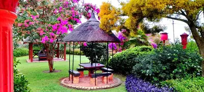 a garden with a table and a gazebo and flowers at Sun and Stars in Benoni