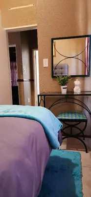a bedroom with a bed and a table and a mirror at 20 Pendleberry Holiday Resort in Bela-Bela