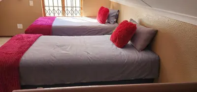 two beds with red and pink pillows in a room at 20 Pendleberry Holiday Resort in Bela-Bela