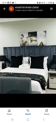 a bedroom with a large bed with a blue headboard at KGADITSE ROAD LODGE in Moletlane