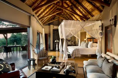 a bedroom with a bed and a living room at Lion Sands - Tinga Lodge in Skukuza