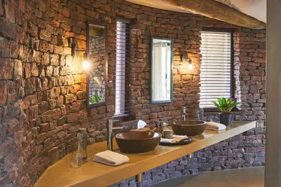 a bathroom with two sinks in a brick wall at Marataba Safari Lodge in Hartbeestfontein