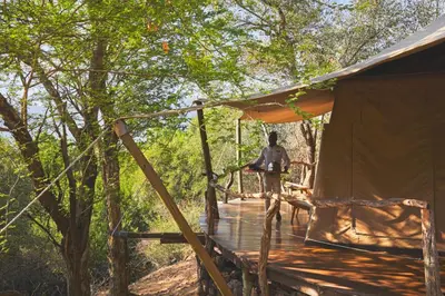 a man standing on a wooden deck next to a tent at Marataba Safari Lodge in Hartbeestfontein