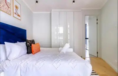 a bedroom with a large white bed with an orange pillow at Ellipse Cassini @ Waterfall (Fili) in Midrand