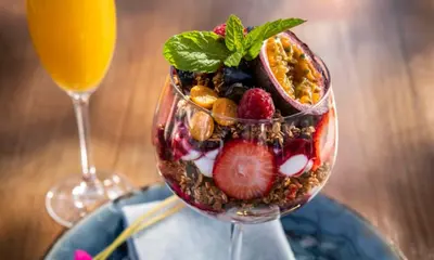 a bowl of fruit and nuts with a glass of juice at Ellipse Cassini @ Waterfall (Fili) in Midrand