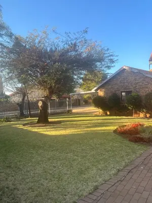 a tree in the middle of a yard with a house at Centurion Family House in Centurion