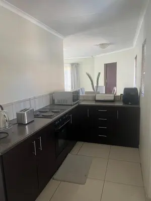 a kitchen with black cabinets and a stove top oven at Centurion Family House in Centurion