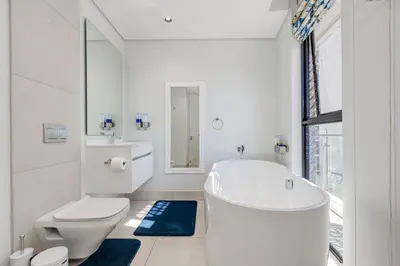 a white bathroom with a tub and a toilet at The Executive Apartment in Ellipse Waterfall City in Midrand