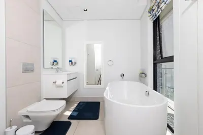a white bathroom with a tub and a toilet at The Executive Apartment in Ellipse Waterfall City in Midrand