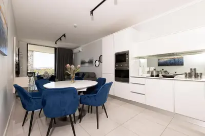 a kitchen and dining room with a table and blue chairs at The Executive Apartment in Ellipse Waterfall City in Midrand