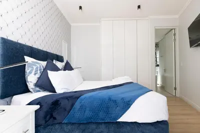 a bedroom with a bed with blue and white sheets at The Executive Apartment in Ellipse Waterfall City in Midrand
