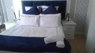a bedroom with a large bed with blue and white pillows at The Executive Apartment in Ellipse Waterfall City in Midrand