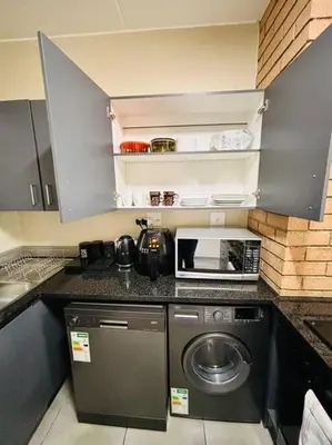 a kitchen with a washing machine and a microwave at The Place at Mall of Africa 2 in Midrand