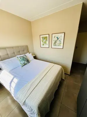 a bed in a bedroom with two pictures on the wall at The Place at Mall of Africa 2 in Midrand
