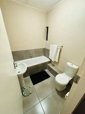 a bathroom with a white toilet and a sink at The Place at Mall of Africa 2 in Midrand