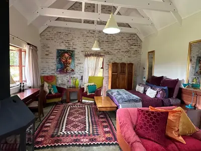 a living room with purple furniture and a brick wall at Giverny in Dullstroom
