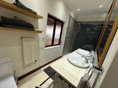 a bathroom with two sinks and a shower with a window at Giverny in Dullstroom