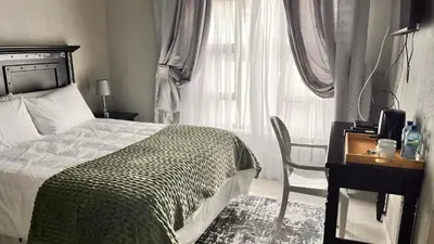 a bedroom with a bed and a chair and a window at Nandoni Junction GuestVilla, Nandoni Thohoyandou in Vendaland