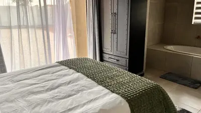 a bedroom with a bed and a tub and a window at Nandoni Junction GuestVilla, Nandoni Thohoyandou in Vendaland
