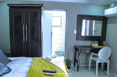 a bedroom with a bed and a desk and a mirror at Nandoni Junction GuestVilla, Nandoni Thohoyandou in Vendaland