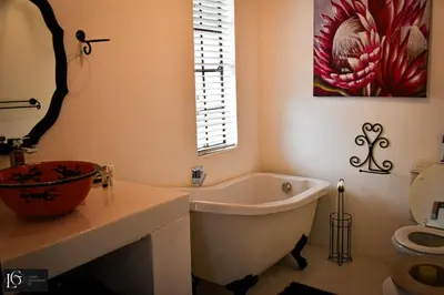 a bathroom with a tub and a painting on the wall at Luxury GuesthouseCo RomanticaHouse in Marloth Park
