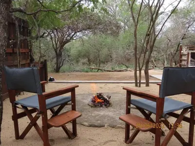 two chairs sitting next to a camp fire at Luxury GuesthouseCo RomanticaHouse in Marloth Park