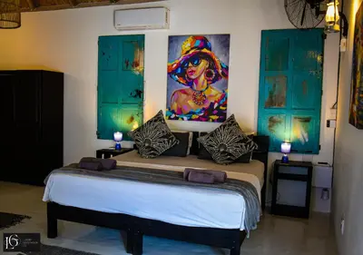 a bedroom with a bed with a painting on the wall at Luxury GuesthouseCo RomanticaHouse in Marloth Park
