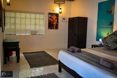 a bedroom with a bed and a desk and a window at Luxury GuesthouseCo RomanticaHouse in Marloth Park