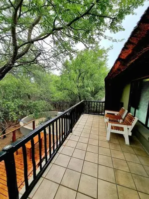 a balcony with a bench on a house at Luxury GuesthouseCo FarmHouse in Marloth Park