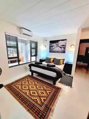 a bedroom with a bed and a rug at Luxury GuesthouseCo FarmHouse in Marloth Park