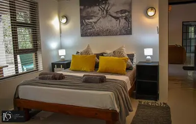 a bedroom with a large bed with yellow pillows at Luxury GuesthouseCo FarmHouse in Marloth Park