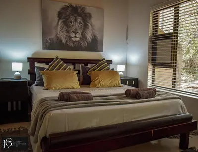 a bedroom with a large bed with a lion picture on the wall at Luxury GuesthouseCo FarmHouse in Marloth Park