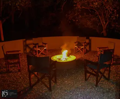 a group of chairs around a fire pit at night at Luxury GuesthouseCo FarmHouse in Marloth Park