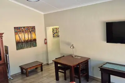 a living room with a table and a flat screen tv at Hornbill Helipad 2 in Centurion