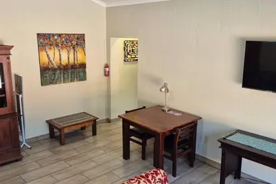 a living room with a table and a tv at Hornbill Helipad 2 in Centurion