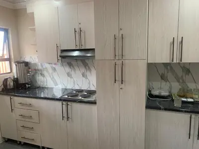a kitchen with white cabinets and black counter tops at Rethabile Guesthouse in Bochum