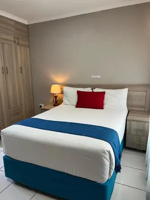 a bedroom with a large bed with a red pillow at Rethabile Guesthouse in Bochum