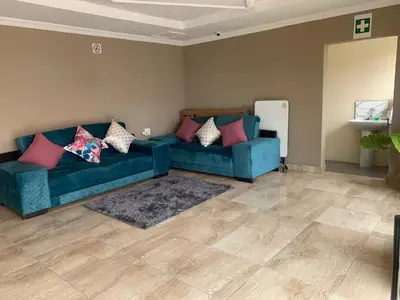 a living room with a blue couch and pink pillows at Rethabile Guesthouse in Bochum