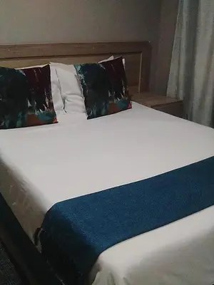 a white bed with two pillows and a blue blanket at Rethabile Guesthouse in Bochum