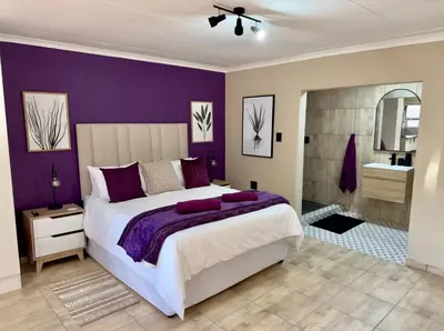 a purple bedroom with a large bed and a bathroom at Sugar Plum Rest in Polokwane