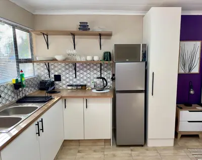 a kitchen with white cabinets and a refrigerator at Sugar Plum Rest in Polokwane