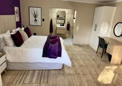 a bedroom with a large white bed and a desk at Sugar Plum Rest in Polokwane