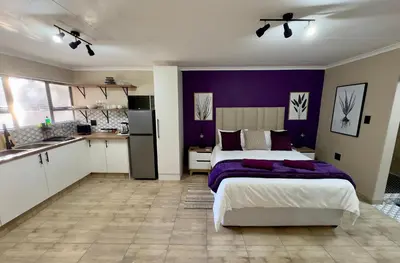 a bedroom with a bed and a purple wall at Sugar Plum Rest in Polokwane