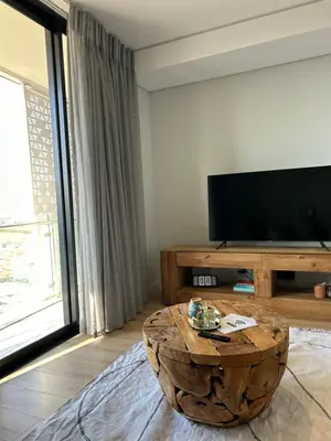 a living room with a television and a coffee table at Thando's Luxury Stays at Ellipse, Waterfall in Midrand