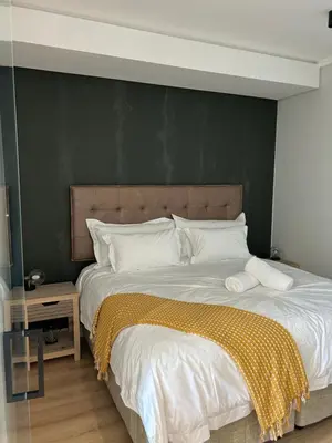 a bedroom with a large bed with a green wall at Thando's Luxury Stays at Ellipse, Waterfall in Midrand