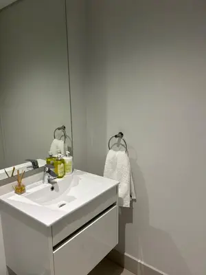 a bathroom with a white sink and a mirror at Thando's Luxury Stays at Ellipse, Waterfall in Midrand
