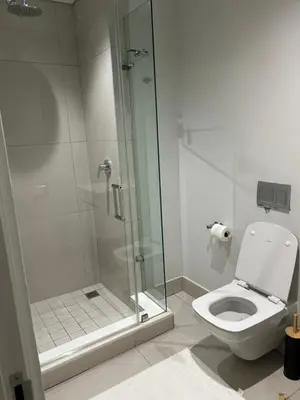 a bathroom with a toilet and a glass shower at Thando's Luxury Stays at Ellipse, Waterfall in Midrand