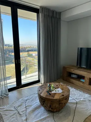a living room with a large window and a coffee table at Thando's Luxury Stays at Ellipse, Waterfall in Midrand